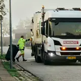 Skraldemand trækker affaldsbeholder hen til skraldebil