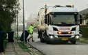 Skraldemand trækker affaldsbeholder hen til skraldebil