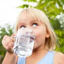 Lille pige drikker et glas vand fra vandhanen